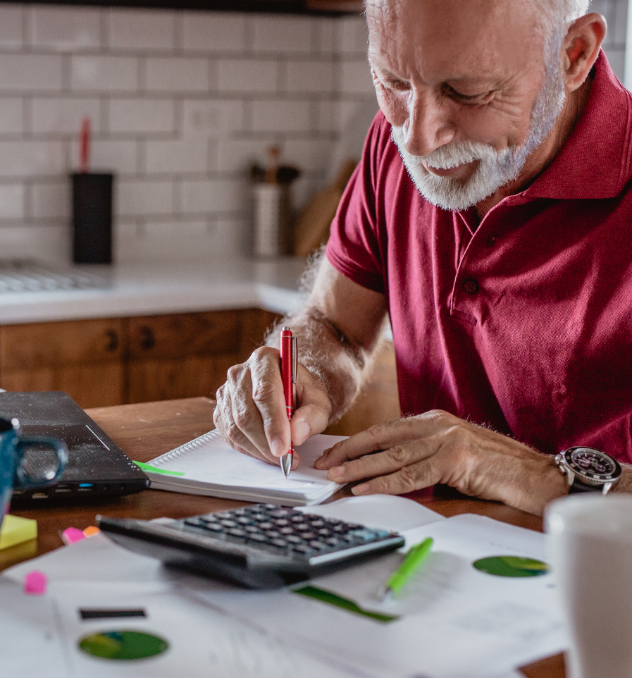 Man writing in notebook while sitting at computer